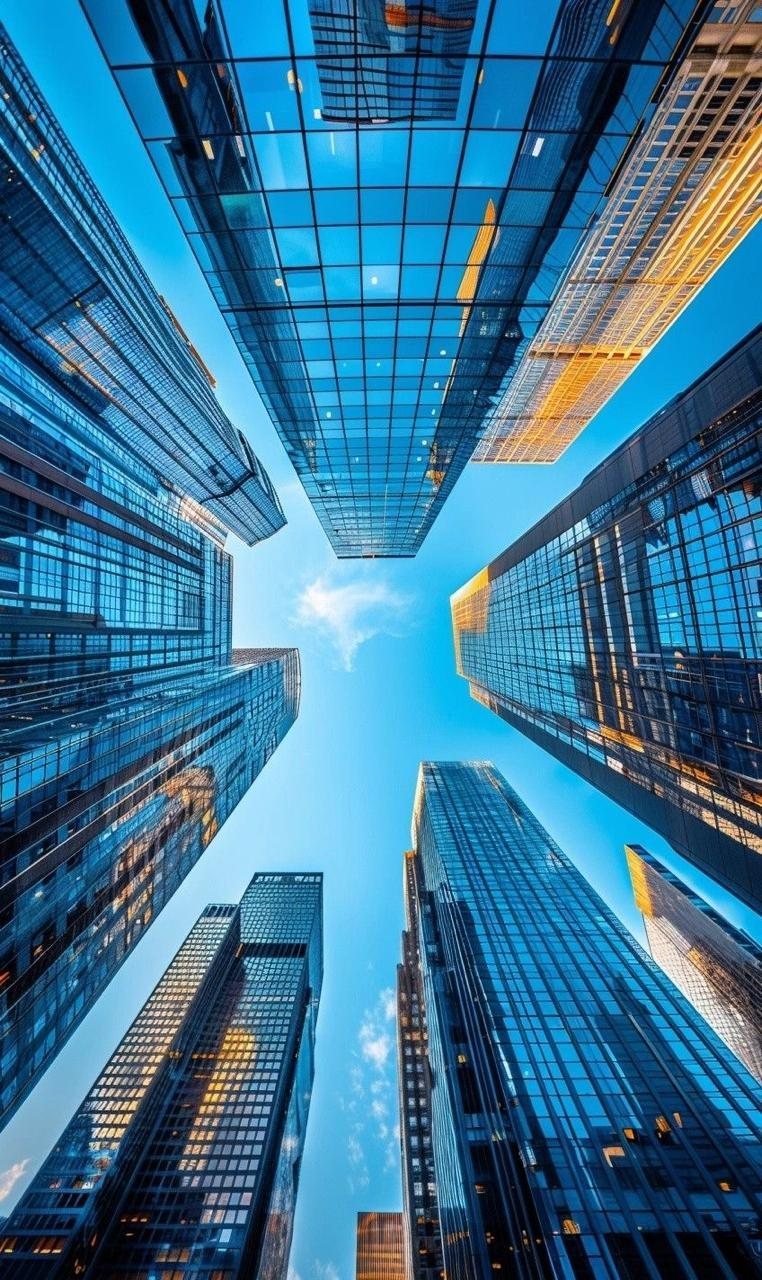 Glass high-rise towers seen from street level against a blue sky